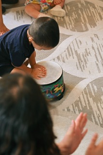 A baby reaching for a hand drum