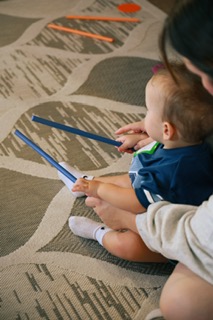 A baby holding a pair of rhythm sticks