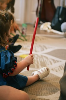 A little girl tapping a rhythm stick